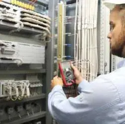 Technicien mesurant une armoire électrique au multimètre